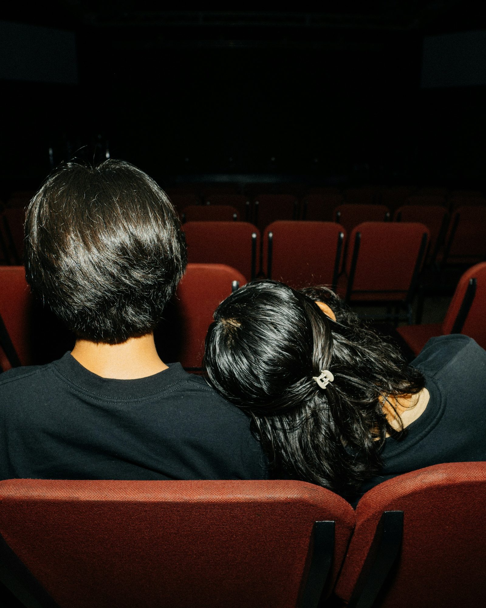 Two friends in red theater seats before the show