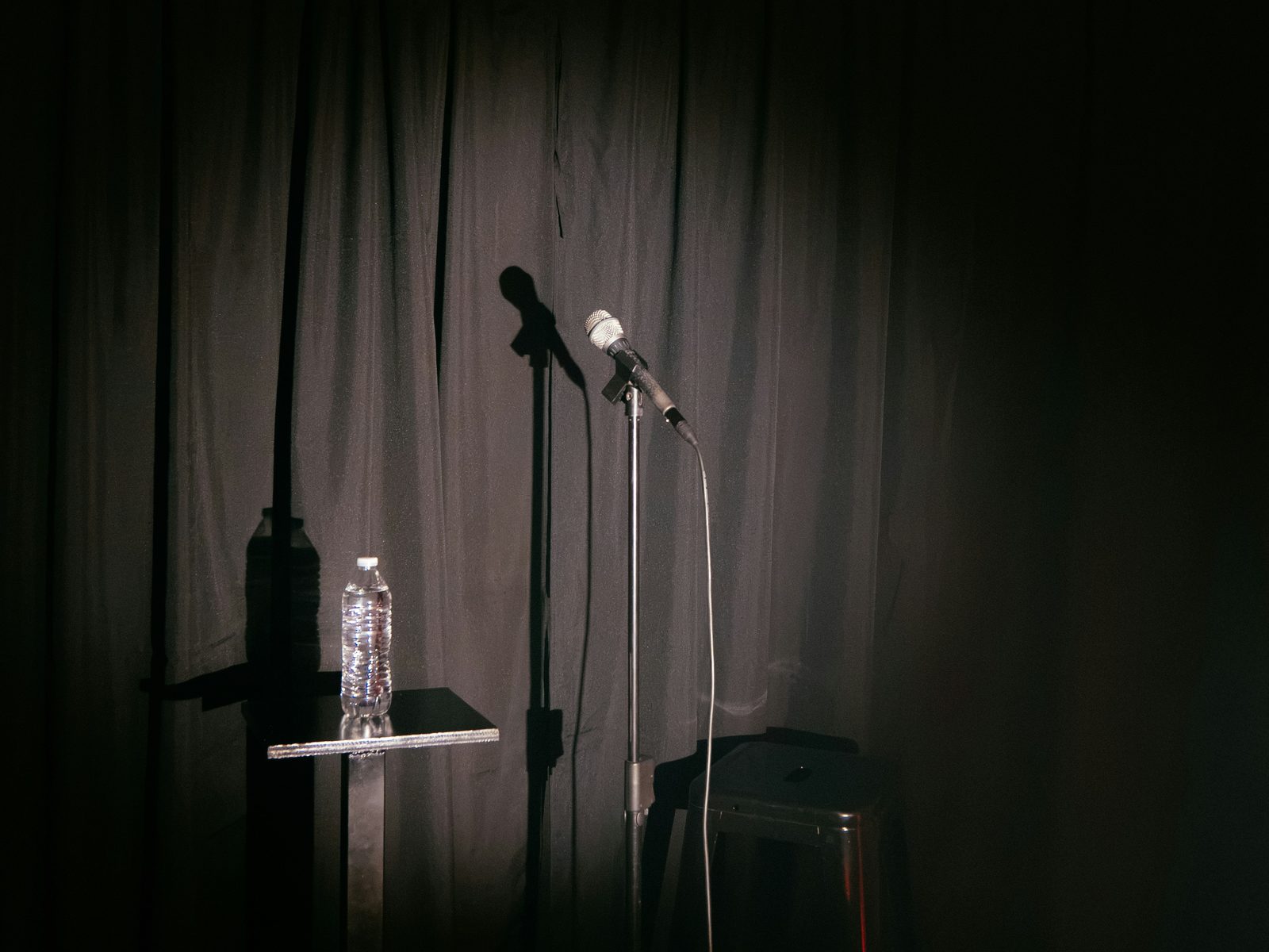 A microphone and stool under a spotlight before a set